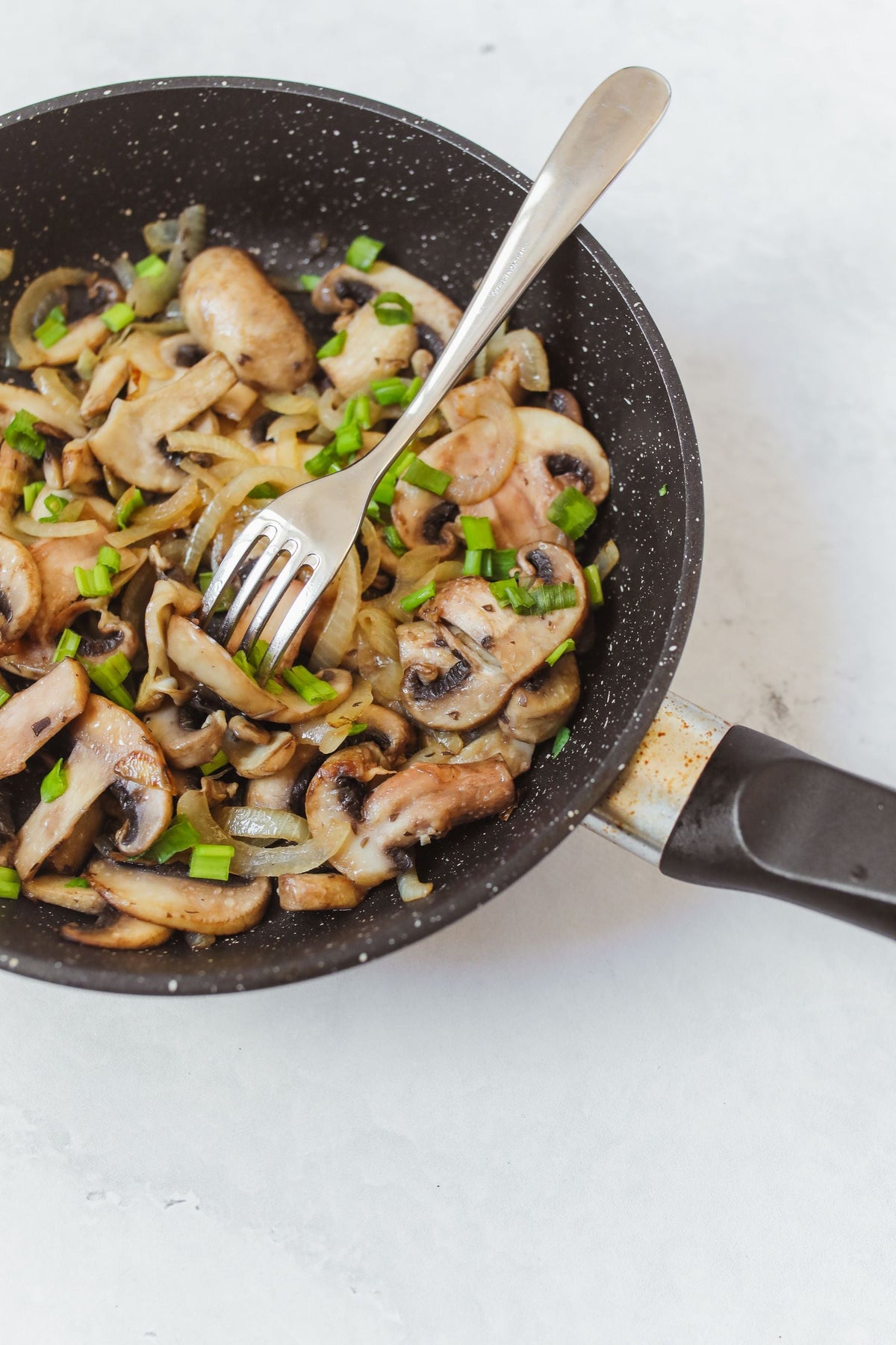 Stockfoto: gebratene Champignons mit Zwiebeln und grünen Kräutern in einer Pfanne. Foto: Polina Tankilevitch / Pexels.