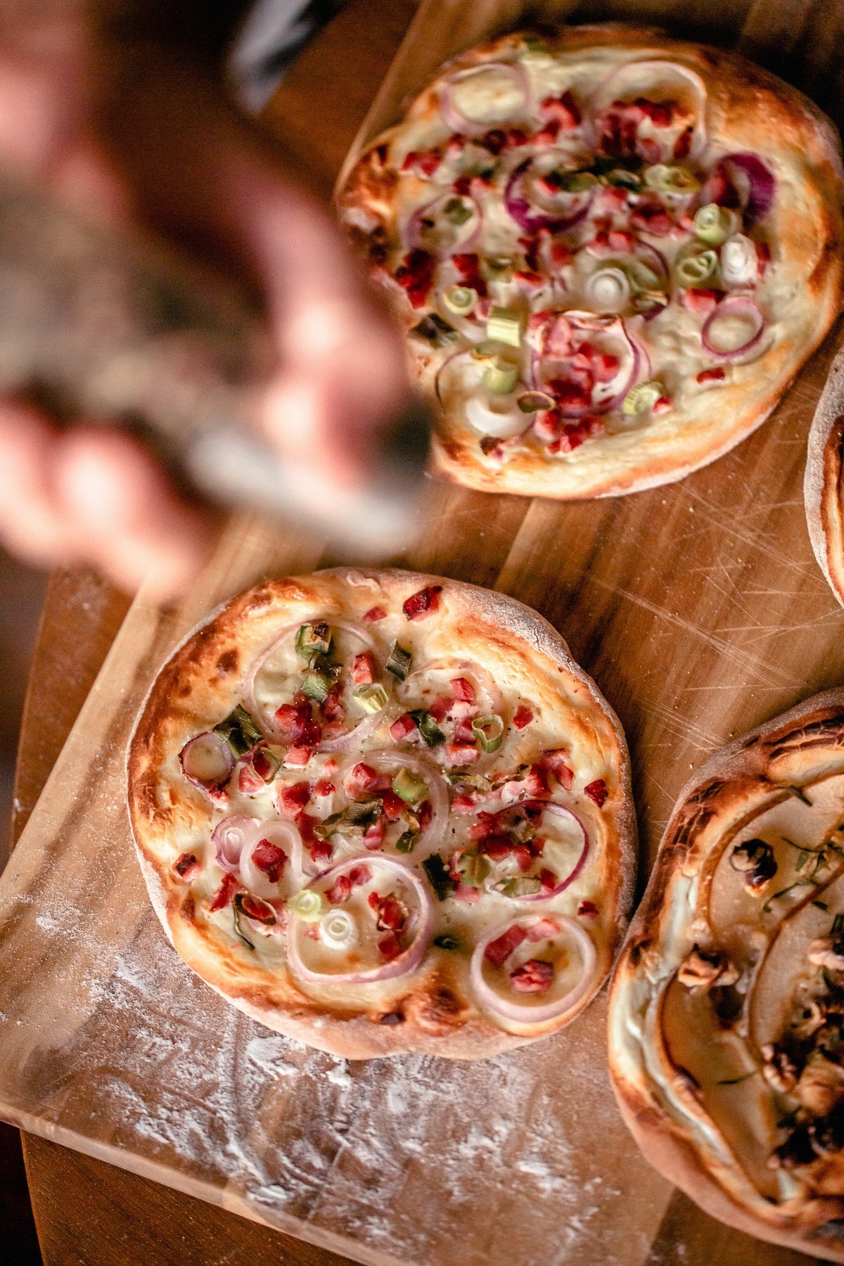 Stockfoto: kleine Flammkuchen mit Speck und roten Zwiebeln auf Holzbrettern. Foto: Chris Reyem / Unsplash.