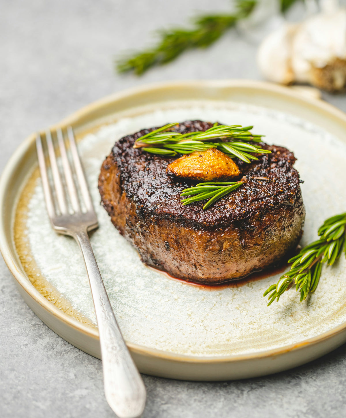 Servieridee: Gebratenes Steak mit Kräutern und einem Stück Butter auf einem hellen Teller. Foto: Chad Montano / Unsplash.