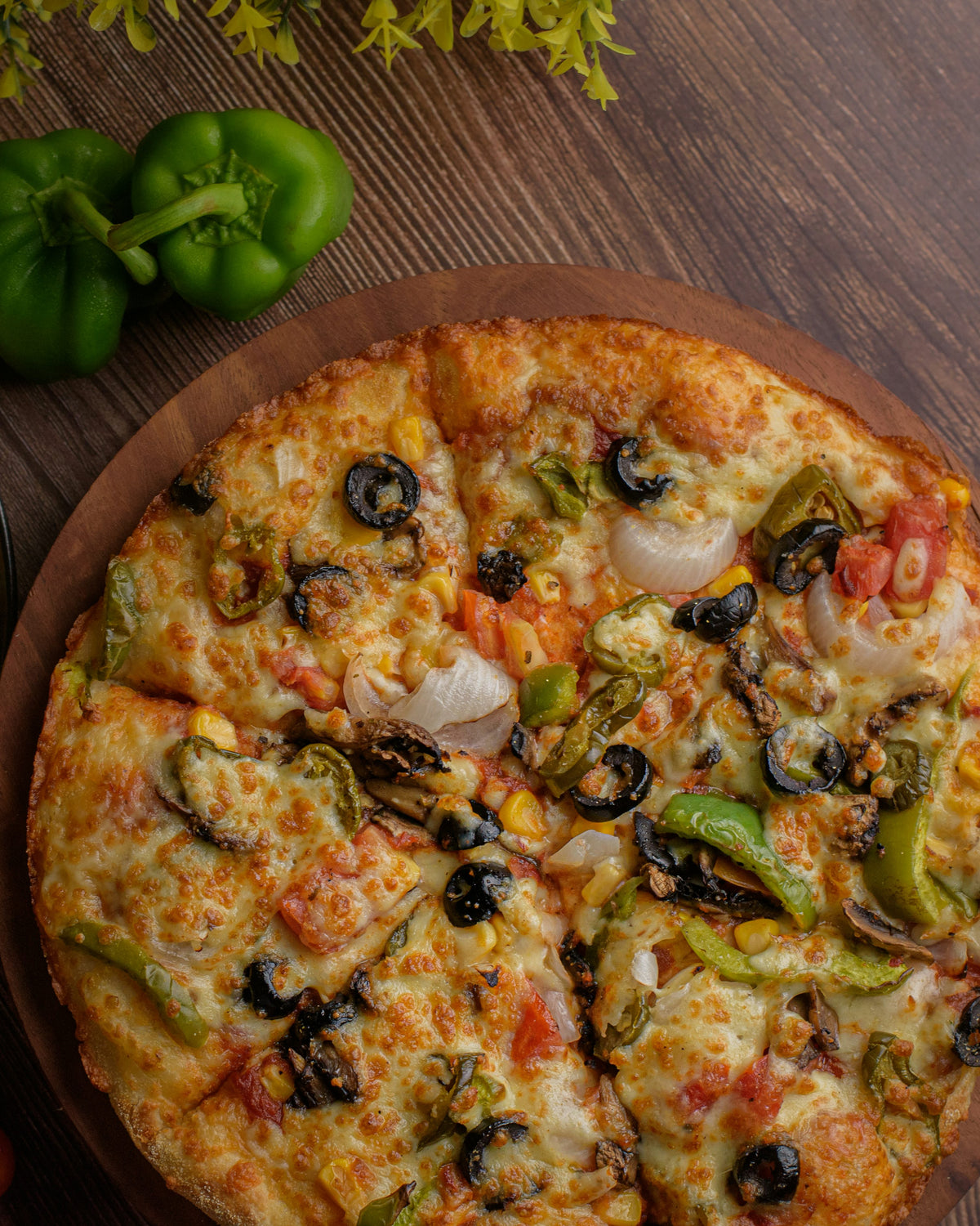Servieridee: Runde Pizza mit sichtbarer Paprika, Pilzen, Zwiebeln und dunklen Oliven auf einem Holzbrett. Foto: Pranjall Kumar / Unsplash.