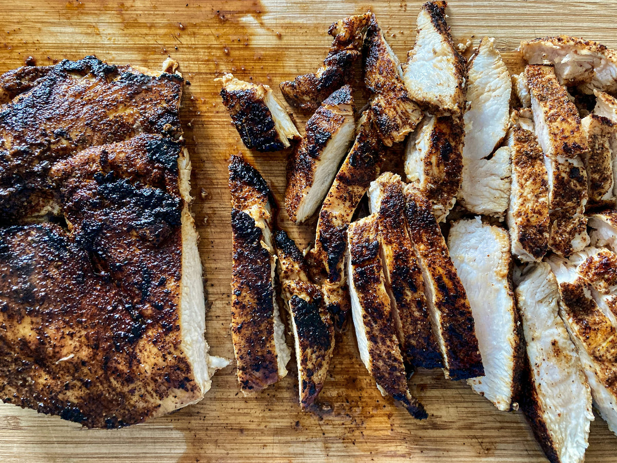 Servieridee: Gebräuntes Hähnchenbrustfleisch wird in Streifen geschnitten und liegt auf einem Holzbrett. Foto: Thomas Park / Unsplash.