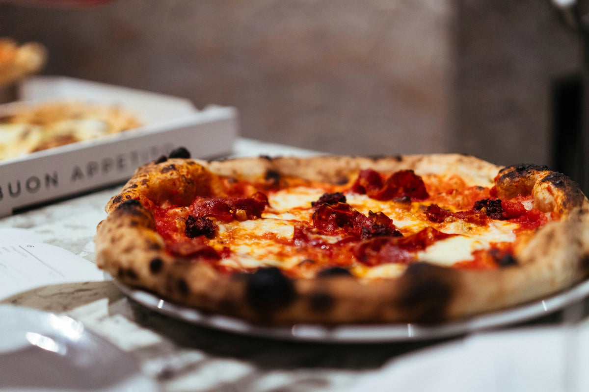 Servieridee: Gebackene runde Pizza mit Salami beziehungsweise Pepperoni, Käse und gebräuntem Rand. Foto: Phil Hearing / Unsplash.