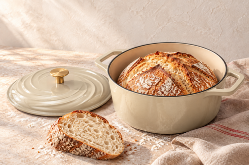 Produktvisualisierung aus dem AMZBBQ Booklet: beiger emaillierter Brotbacktopf mit Brot und abgelegtem Deckel
