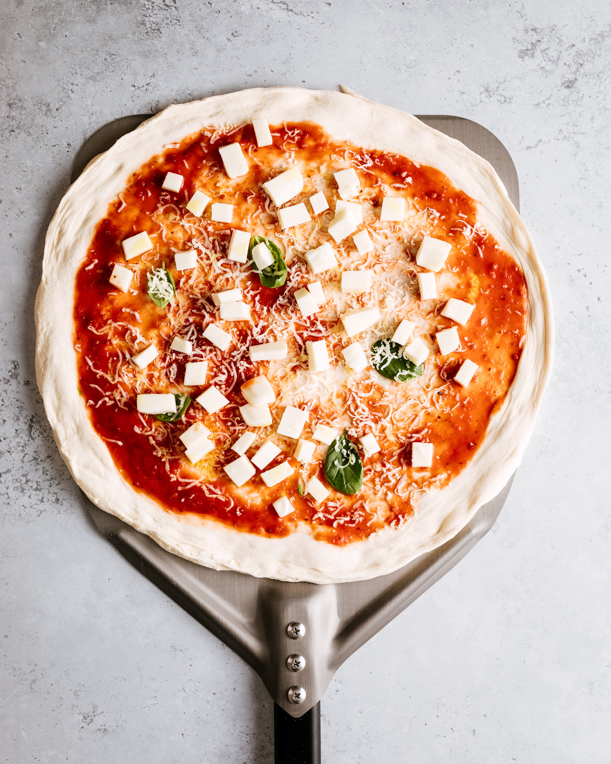 Rohe belegte Pizza auf einem AMZBBQ Pizzaschieber
